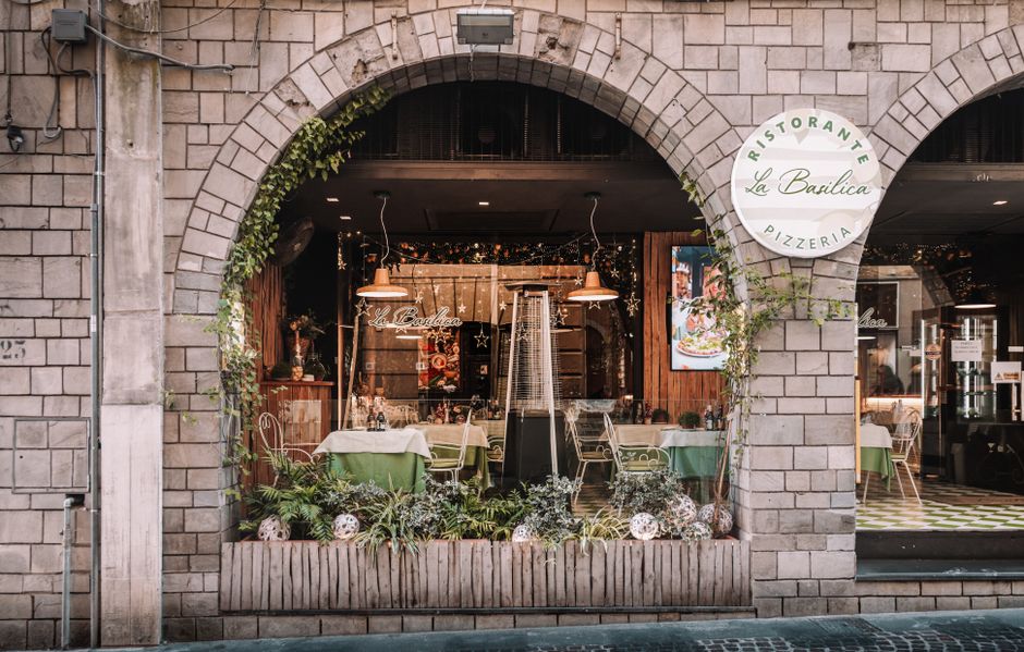 Beautiful Italian pizzeria entrance with classic stone arches and inviting decor in a cozy outdoor setting.